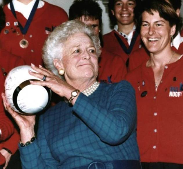 En esta foto de archivo tomada el 6 de febrero de 1992, la exprimera dama estadounidense Barbara Bush se prepara para lanzar un balón de rugby en Washington, DC, después de recibirlo de Mary Sullivan (R), capitana del equipo nacional de rugby femenino de Estados Unidos. El equipo de Estados Unidos que ganó la Copa del Mundo, recibió el Premio Team Spirit de la Sra. Bush. AFP