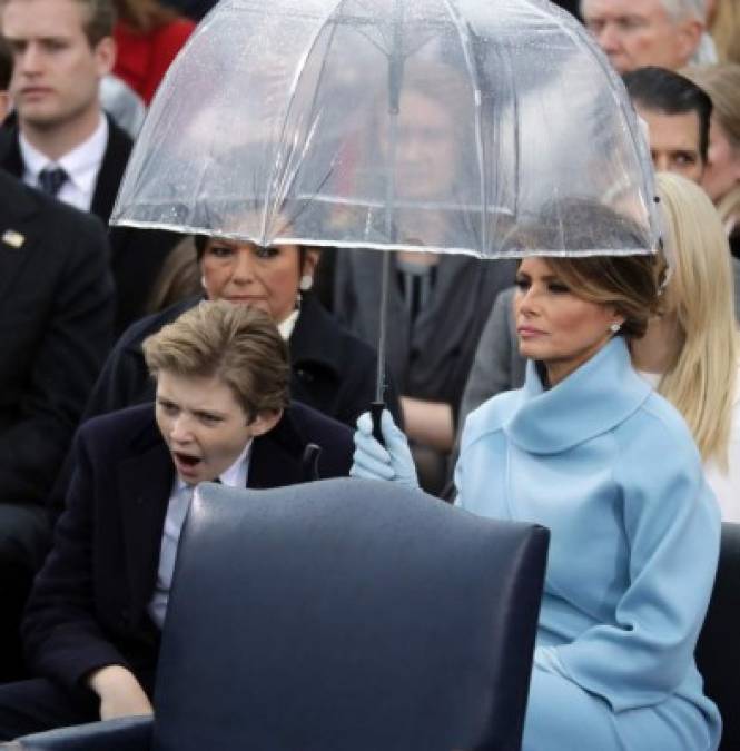 La primera dama, Melania Trump, soporta estoicamente la lluvia durante la ceremonia. Le acompaña su hijo, un aburrido Barron Trump.