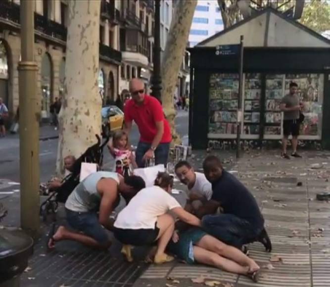 This video grab obtained on August 17, 2017 from the instagram account carlos_tg_32_ shows people tending to an injured woman after a van ploughed into the crowd, killing 13 persons and injuring several others, on the Rambla in Barcelona.<br/>At least 13 people were killed today when a driver deliberately slammed a van into crowds on Las Ramblas, Barcelona's most famous street, in what police said was a 'terror attack'. Two suspects have been arrested over the attack, according to Spanish authorities.<br/> / AFP PHOTO / INSTAGRAM / carlos_tg_32_ / RESTRICTED TO EDITORIAL USE - MANDATORY CREDIT 'AFP PHOTO / INSTAGRAM account carlos_tg_32_' - NO MARKETING NO ADVERTISING CAMPAIGNS - DISTRIBUTED AS A SERVICE TO CLIENTS<br/><br/>