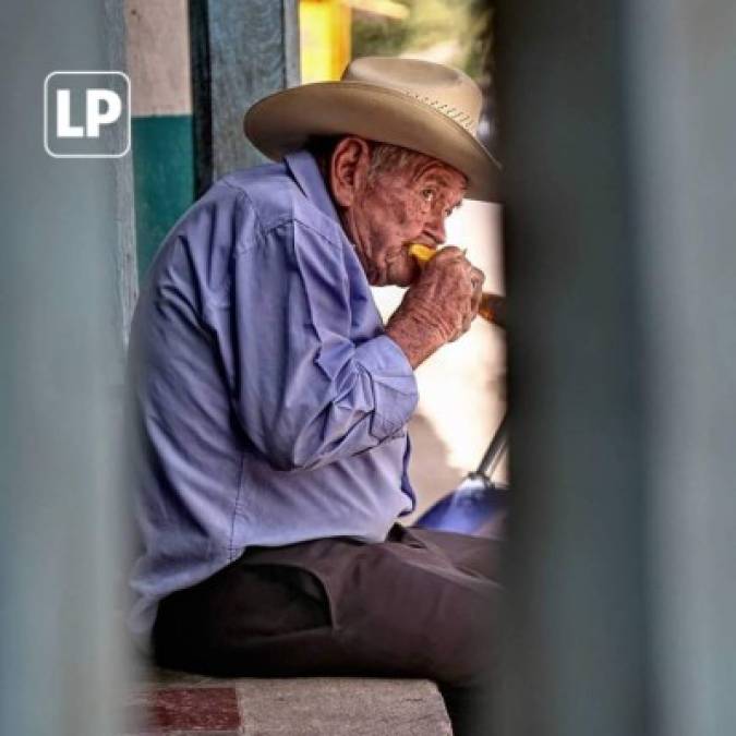 Este humilde abuelo disfruta la tarde mientras come un delicioso mango.