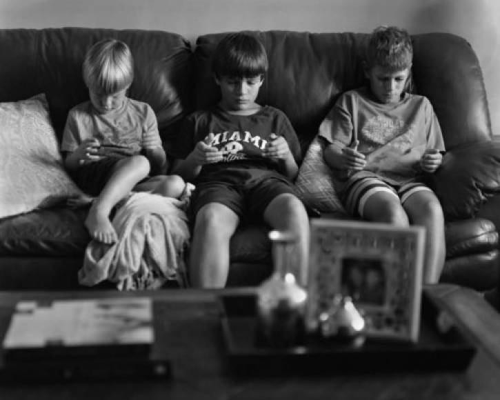 Un grupo de niños en el sofá con sus dispositivos móviles muestra como estos aparatos han desplazado los juegos tradicionales de los pequeños.
