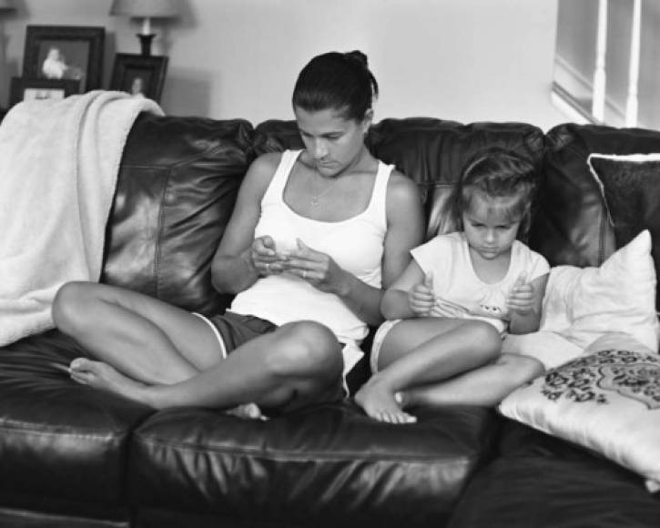 Los padres revisan sus tareas en línea mientras supervisan a sus hijos jugar en sus dispositivos.