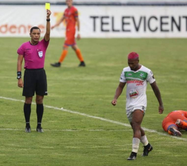 Víctor Arauz, lateral del Platense, lució un llamativo look con el pelo teñido de rosa. El árbitro Selvin Brown le muestra tarjeta amarilla por una falta cometida.