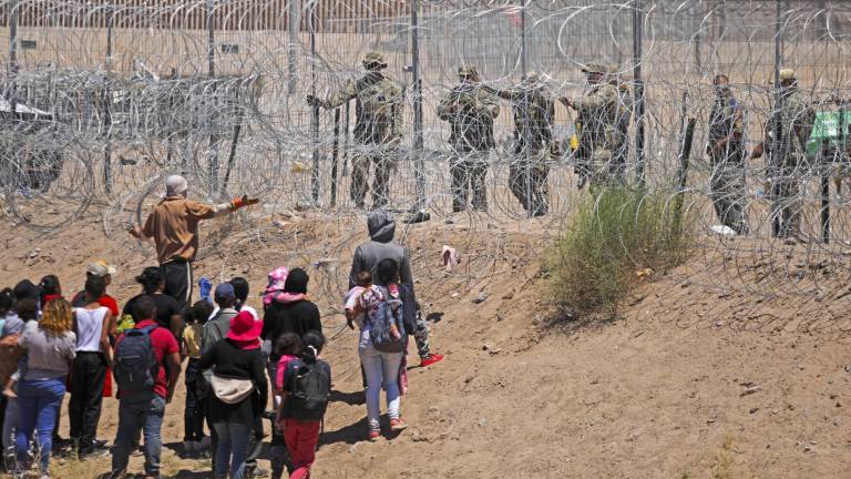 Un grupo de migrantes habla con agentes de la Guardia Nacional de Texas en la frontera entre EEUU y México.