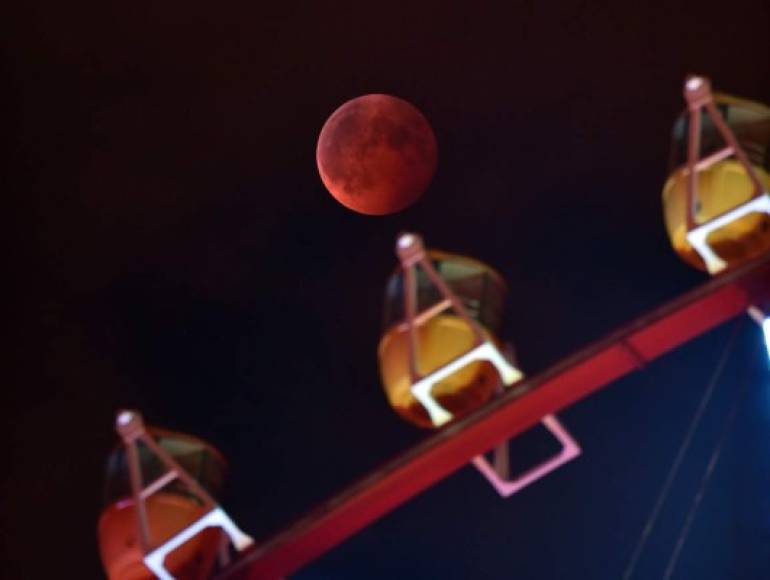 Un eclipse total de Luna se ve detrás de una rueda de la fortuna en Tokio, el 8 de octubre de 2014. AFP