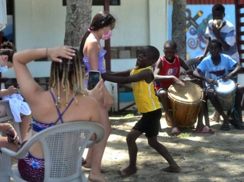 Niños garífunas tocan música tradicional 'punta', en el municipio de Tela, Atlántida, para un grupo de personas que aprovecharon el fin de semana para hacer turismo interno. AFP