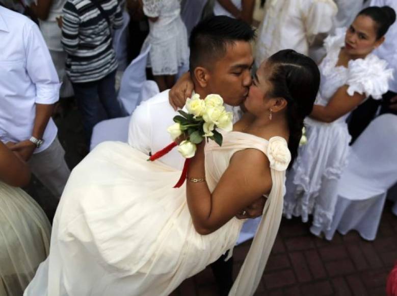 Una pareja sella su enlace con un beso en una boda masiva con motivo del Día de San Valentín en Noveleta, Filipinas. Al menos 100 parejas de filipinos articiparon en una boda masiva civil oficiada por el alcalde de Novelata Dino Reyes Chua.