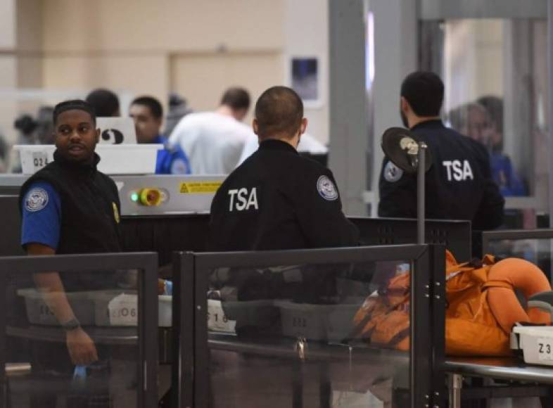 Transportation Security Administration officers (TSA) stand screen passengers at the departure area of the Los Angeles International Airport in Los Angeles, California, on 5 January, 2019. - TSA staff are taking sick leave in record numbers since the partial government shutdown forced them to work without pay from December 22, 2018. Shortly after the new Congress was sworn in on January 4, 2019, the House approved legislation to fund homeland security operations until February 8 and several other agencies through September -- but no money for a wall. Trump has said he would veto any bill that does not include funding for the barrier and the Republican-run Senate has said it would not consider anything that does not pass muster with the president. (Photo by Mark RALSTON / AFP)