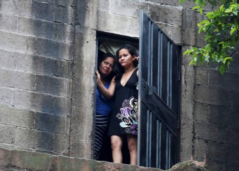 Dos mujeres observan la escena donde cuatro personas fueron asesinadas este viernes cerca a un barrio marginal al oriente de Tegucigalpa (Honduras). EFE