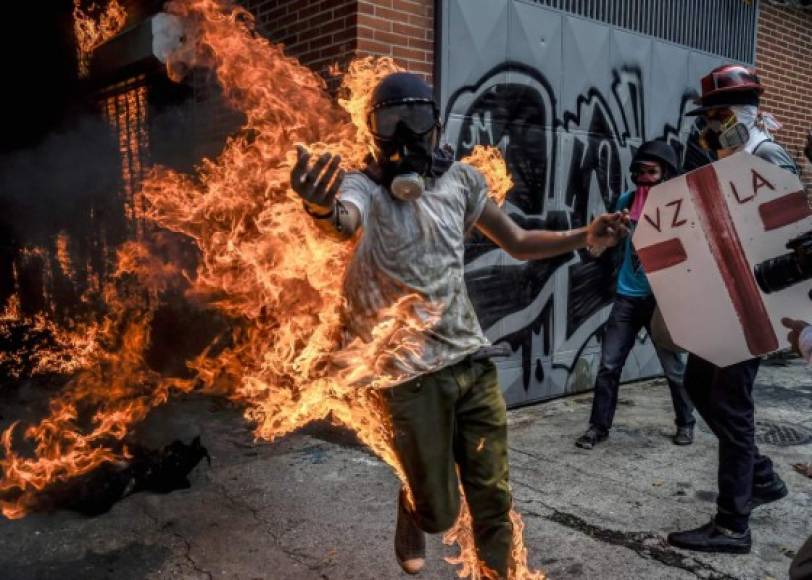 Un manifestante coge fuego al encontrarse muy cerca de un vehículo incendiado.