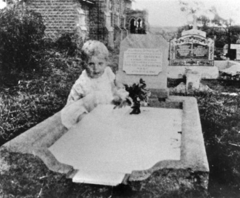 Esta imagen fue tomada por una mujer llamada señora Andrews, mientras visitaba la tumba de su hija que murió de 17 años en un cementerio en Queensland, Australia, en la década de 1940. La señora Andrews no vio nada inusual mientras tomó esta fotografía de la tumba de su hija, pero cuando ella la reveló, se sorprendió al ver la aparición de lo que parecía el fantasma de una pequeña niña sentada en la tumba. <br/><br/>La señora Andrews fue incapaz de reconocer al niño o niña, ni creía que el fantasma fuera su hija en su juventud. Tras realizar investigaciones adicionales, los investigadores paranormales encontraron que la tumba de la hija de la señora Andrews estaba muy cerca de la tumba de dos niñas.