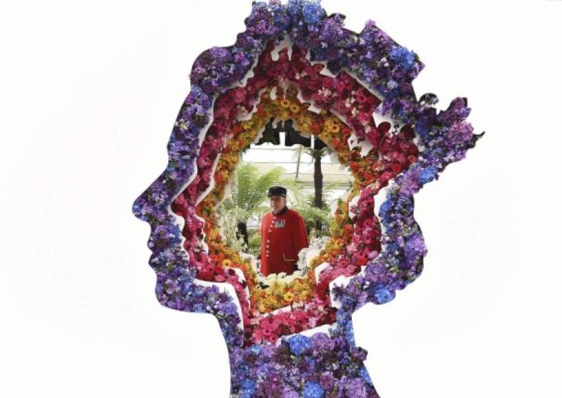 Un jubilado de Chelsea posa detrás de la instalación floral con la silueta de la reina Isabell II de Inglaterra titilada 'Detrás de cada gran florista', diseñada por Veevers Carter, durante la Exposición de flores de Chelsea, Londres.