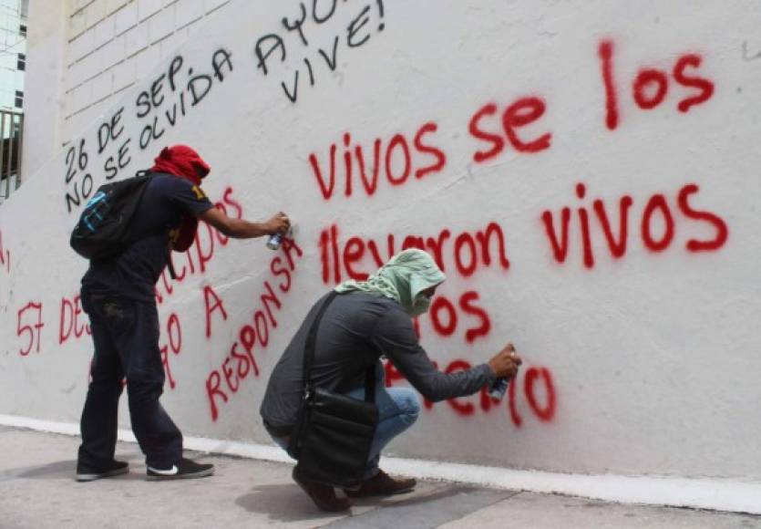 Estudiantes de Ayotzinapa pintan graffitis durante la protesta en los aledaños del Congreso de Guerrero.
