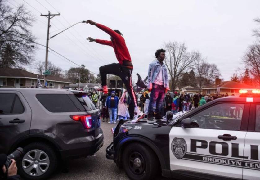 BROOKLYN CENTER, MN - APRIL 11: A man jumps between two police cruisers as people confront police on April 11, 2021 in Brooklyn Center, Minnesota. Protesters took to the streets today after 20 year old Daunte Wright was shot and killed during a traffic stop by members of the Brooklyn Center police. Stephen Maturen/Getty Images/AFP<br/><br/>== FOR NEWSPAPERS, INTERNET, TELCOS & TELEVISION USE ONLY ==<br/><br/>