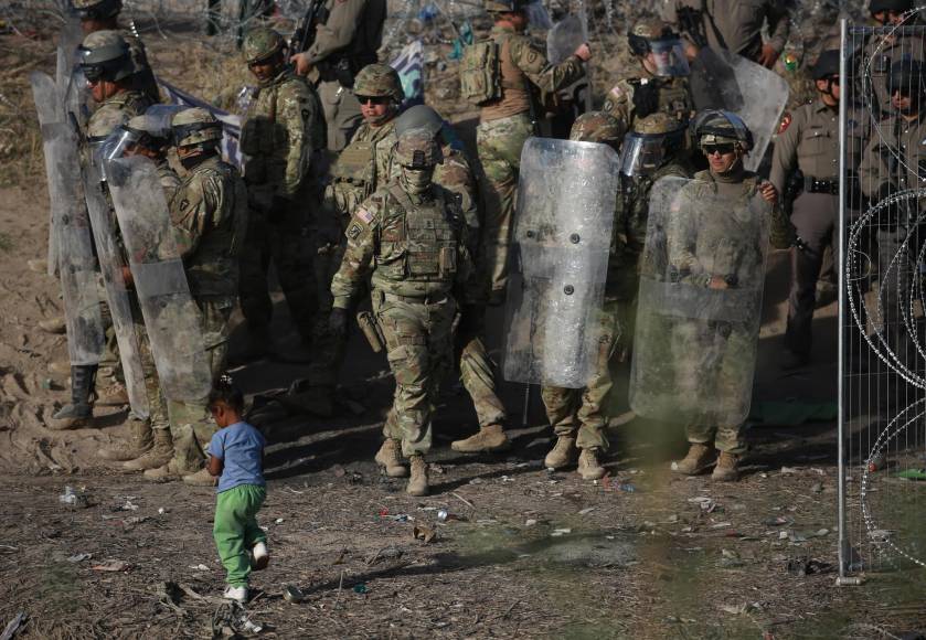  Una niña camina frente a integrantes de la Guardia Nacional de Texas, mientras vigilan este viernes la entrada de migrantes que permanecen en las inmediaciones del la frontera con Estados Unidos, en Ciudad Juárez.