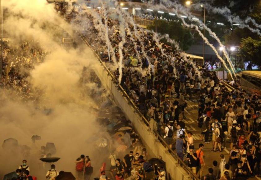 Cientos de manifetantes huyen de los gases lacrimógenos lanzados por la policía china, quienes buscaban dispersar la masiva protesta.