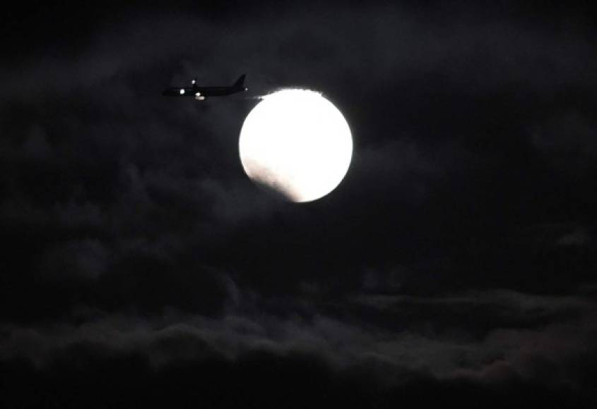 Un avión vuela en el momento que inicia de un eclipse total de Luna en Yokkaichi, centro de Japón, el 8 de octubre de 2014. AFP