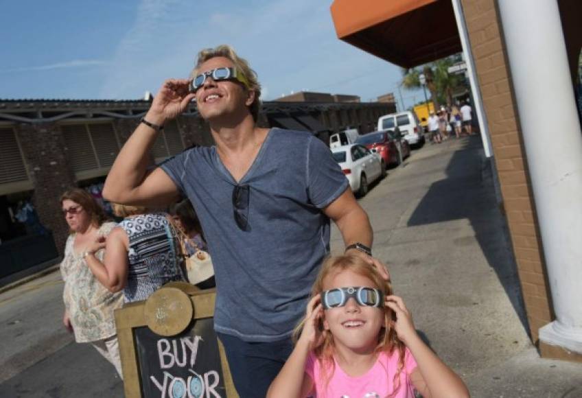 Nikos Spyridonos and his daughter Zoe try out eclipse glasses ahead of the total solar eclipse in Charleston, South Carolina, on August 20, 2017. / AFP PHOTO / MANDEL NGAN