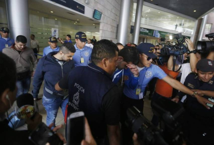 Los detenidos cuando eran conducidos por las autoridades fuera del aeropuerto.