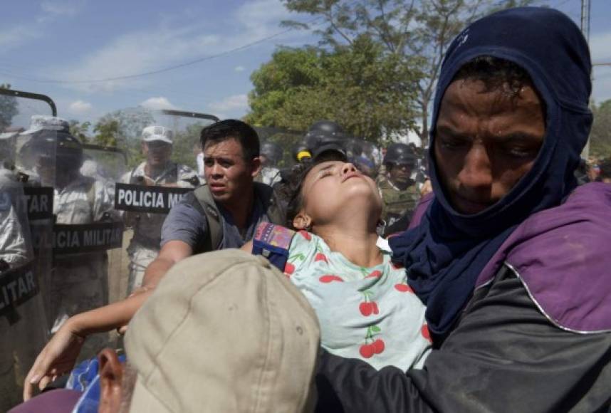 A Central American migrant - part of a group of mostly Hondurans travelling on caravan to the US- carryings a girl after Mexican security forces prevent them to illegally cross into Mexico in Ciudad Hidalgo, Mexico, on January 20, 2020. - Hundreds of Central Americans from a new migrant caravan tried to enter Mexico by force Monday by crossing the river that divides the country from Guatemala, prompting the National Guard to fire tear gas, an AFP correspondent said. (Photo by ISAAC GUZMAN / AFP)