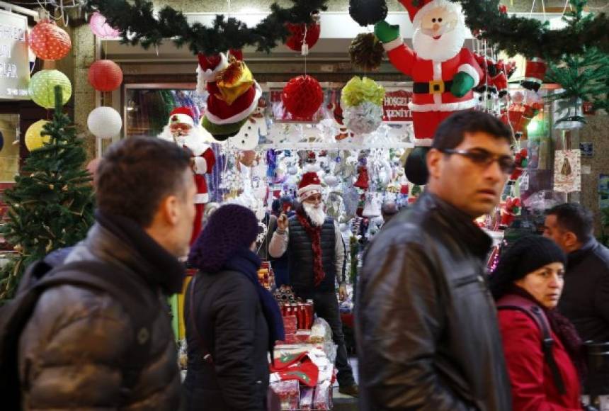 Un vendedor disfrazado de Papa Noel (c) publicita su mercancía en el bazar Tahtakale del barrio de Eminonu en Estambul (Turquía).