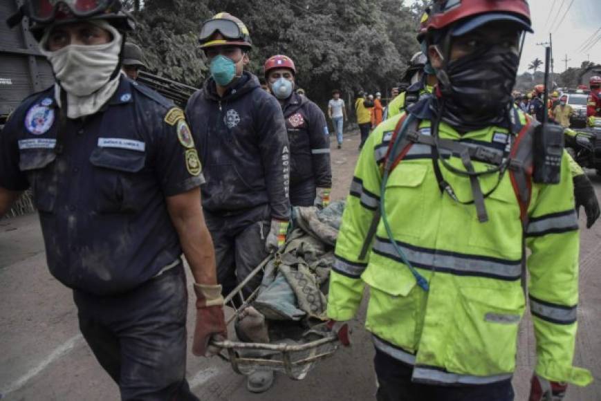 Policías y bomberos trasladan a sus víctimas entre la desolación por las casas destruidas y plantaciones completamente calcinadas por la furia del volcán.