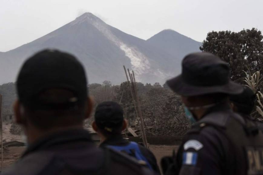 Police officers look at the Fuego Volcano from San Miguel Los Lotes, a village in Escuintla Department, about 35 km southwest of Guatemala City, on June 4, 2018, a day after an eruption.<br/>At least 25 people were killed, according to the National Coordinator for Disaster Reduction (Conred), when Guatemala's Fuego volcano erupted Sunday, belching ash and rock and forcing the airport to close. / AFP PHOTO / Johan ORDONEZ