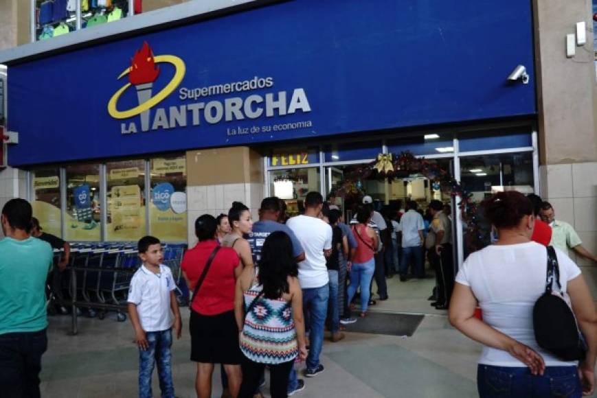 Los sampedranos hacen fila en la entrada del supermercado La Antorcha de la terminal de buses de San Pedro Sula.