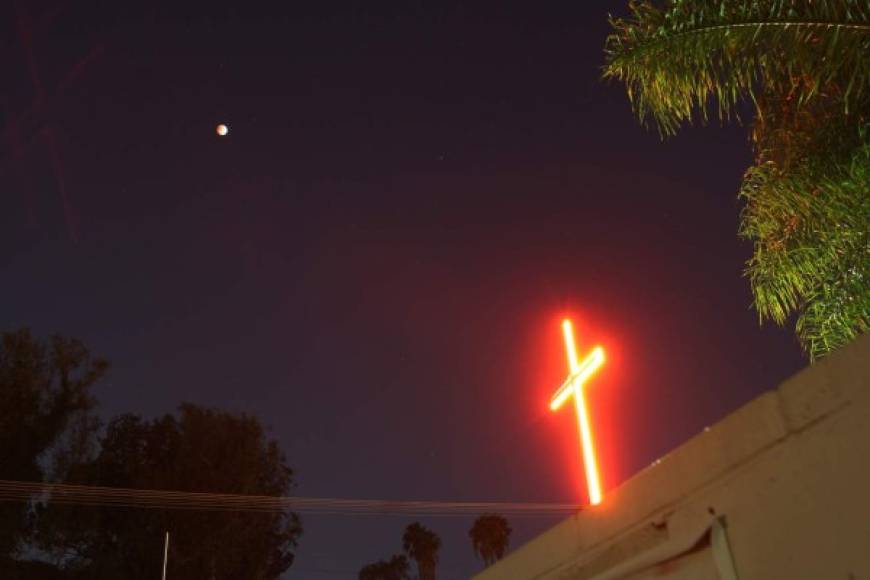 Una cruz religiosa es vista junto a la Luna durante un eclipse total lunar el 8 de octubre de 2014 en Los Angeles, California. AFP
