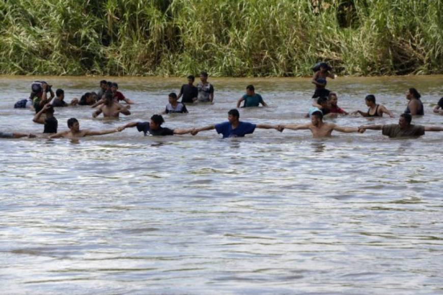 Los migrantes realizaron una cadena humana para mantenerse en pie mientras cruzaban al lado mexicano.