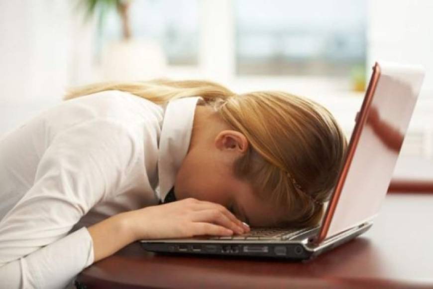 Tired businessman asleep at his desk isolated on white background