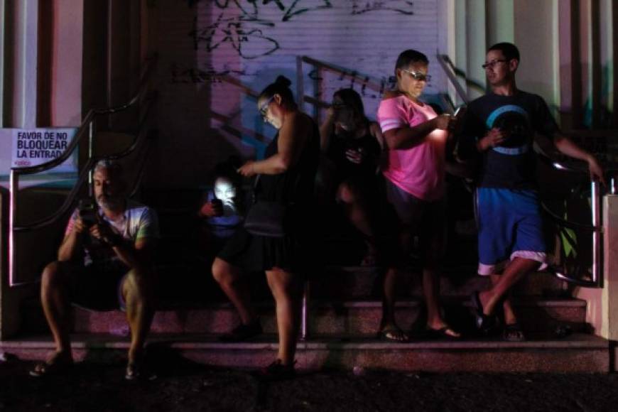Pese al toque de queda, varias personas se reúnen por las noches en uno de los pocos lugares donde hay electricidad en San Juan para intentar comunicarse con sus familiares fuera de la isla.