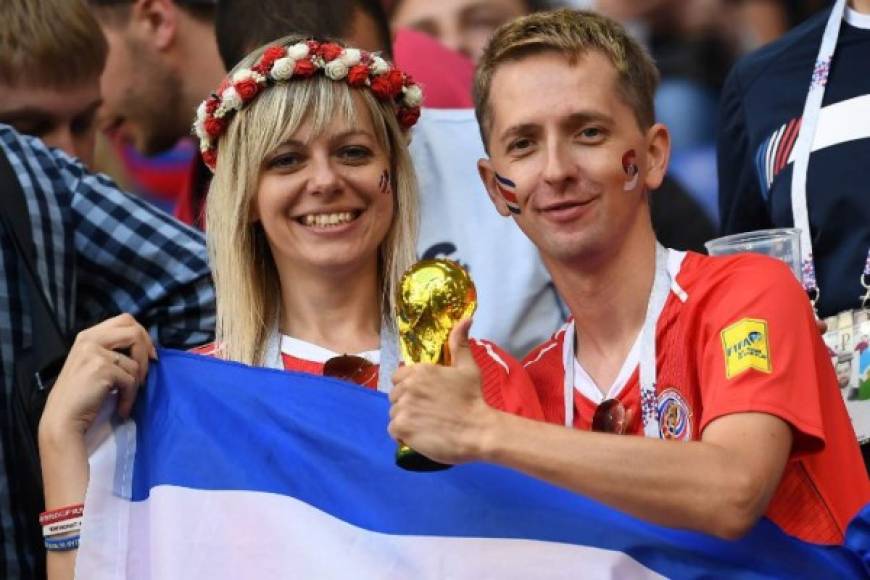 Dos aficionados posan con una réplica de la Copa del Mundo.