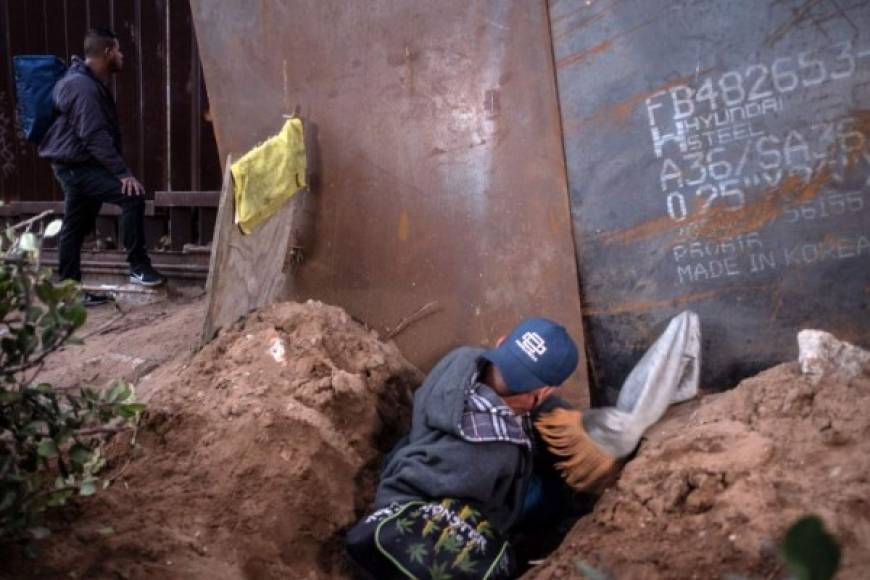 A migrant travelling in a caravan of Central Americans hoping to get to the United States, crosses through a hole on the ground under the metal barrier separating Mexico and the US to cross from Playas de Tijuana in Mexico into the US, on December 4, 2018. - Mexico's new Foreign Minister Marcelo Ebrard met with US Secretary of State Mike Pompeo for a 'friendly' meeting amid tensions over the migrant crisis at the border. Both countries are grappling with how to handle the thousands of Central American migrants who are camped at the common border -- in the short and long terms. (Photo by Guillermo Arias / AFP)