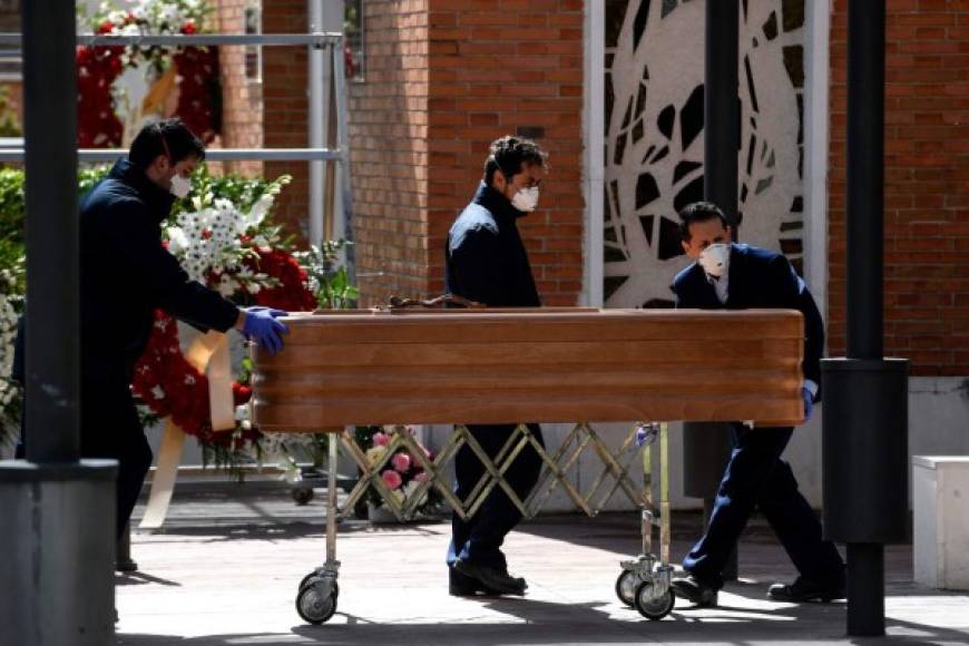 Mortuary employees wearing face masks wheel a coffin into the crematorium of La Almudena cemetery in Madrid on March 24, 2020 during the funeral of a COVID-19 coronavirus victim. - Spain has been one of the worst-hit countries, logging the third-highest number of deaths with the latest figures showing a toll of 2,696. (Photo by OSCAR DEL POZO / AFP)