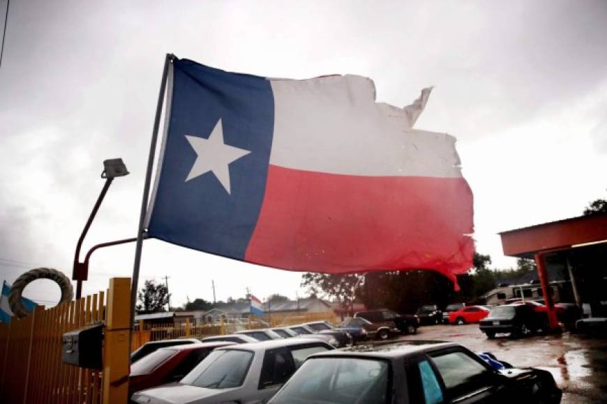 Una rasgada bandera texana ondea en un estacionamiento de Houston Texas.