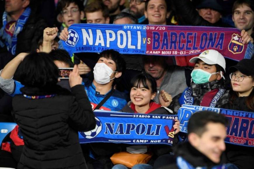 Los fanáticos del fútbol usan máscaras protectoras mientras asisten a los octavos de final de la UEFA Champions League entre el SSC Napoli y el FC Barcelona en el estadio San Paolo en Nápoles el 25 de febrero de 2020. <br/>