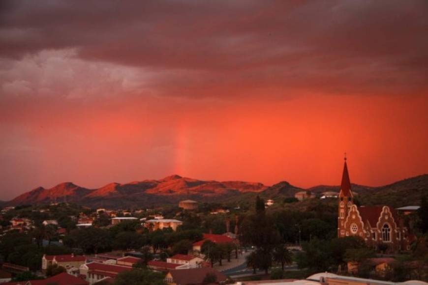 <br/>Vista desde el bar de la azotea Hilton en Windhoek sobre la ciudad, con la iglesia de Cristo, un arcoiris, montañas y un increíble ambiente al atardecer.