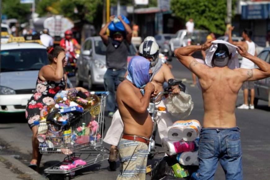 People push lorries with goods after looting a supermarket during protests against the government's reforms in the Institute of Social Security (INSS) in Managua on April 22, 2018.<br/>Violent protests against a proposed change to Nicaragua's pension system have left at least 20 people dead, according to a local human rights body. The Nicaraguan Center for Human Rights said it was still trying to verify figures, but that at least 20 people had been killed since protests erupted in the central American country on April 18 over pension reform. / AFP PHOTO / INTI OCON
