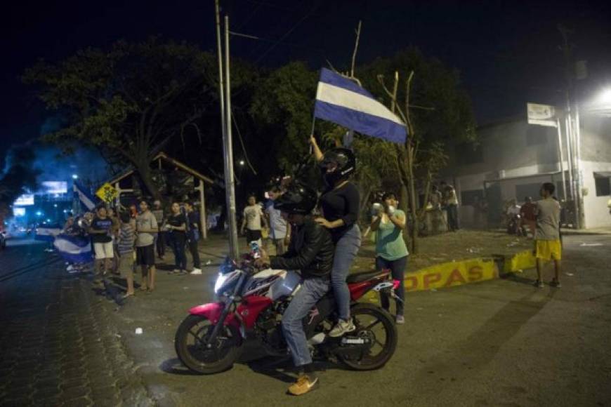 TOPSHOT - Demonstrators sing the national anthem in front of the Police Station during a protest against the government of President Daniel Ortega, in Managua, on April 25, 2018.<br/>A week of brutally repressed anti-government protests in Nicaragua has killed at least 34 people, a leading rights group in the country said Wednesday. The protests were triggered by pension reforms that President Daniel Ortega ended up withdrawing amid mounting condemnation of the harsh police tactics against the demonstrators. / AFP PHOTO / RODRIGO ARANGUA