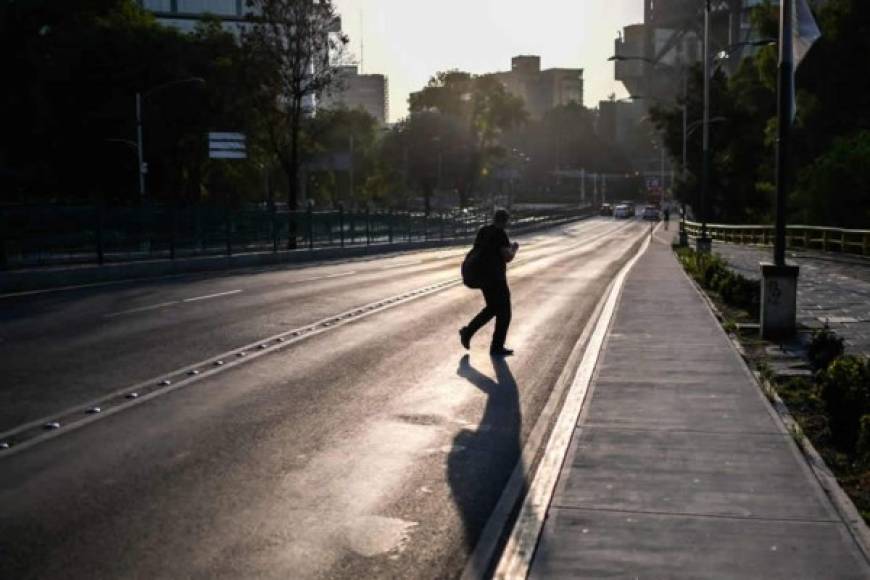 Un hombre cruza hoy una calle casi vacía en la Ciudad de México.