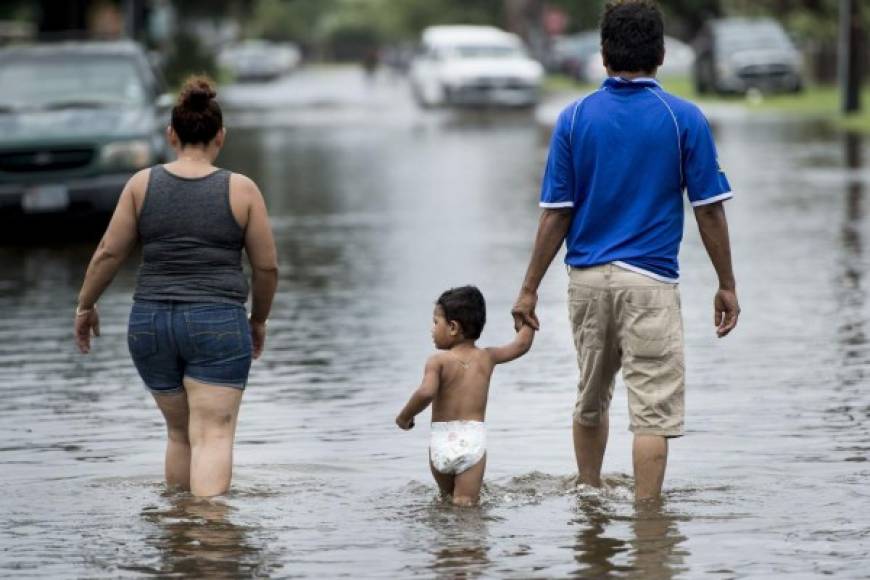 Una pequeña familia recorre una inundada calle en Galveston.