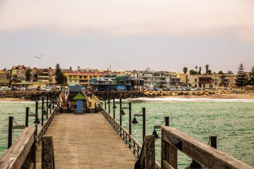 Largo muelle, gente caminando, casas residenciales en la costa de Swakopmund ciudad colonial alemana, Namibia.