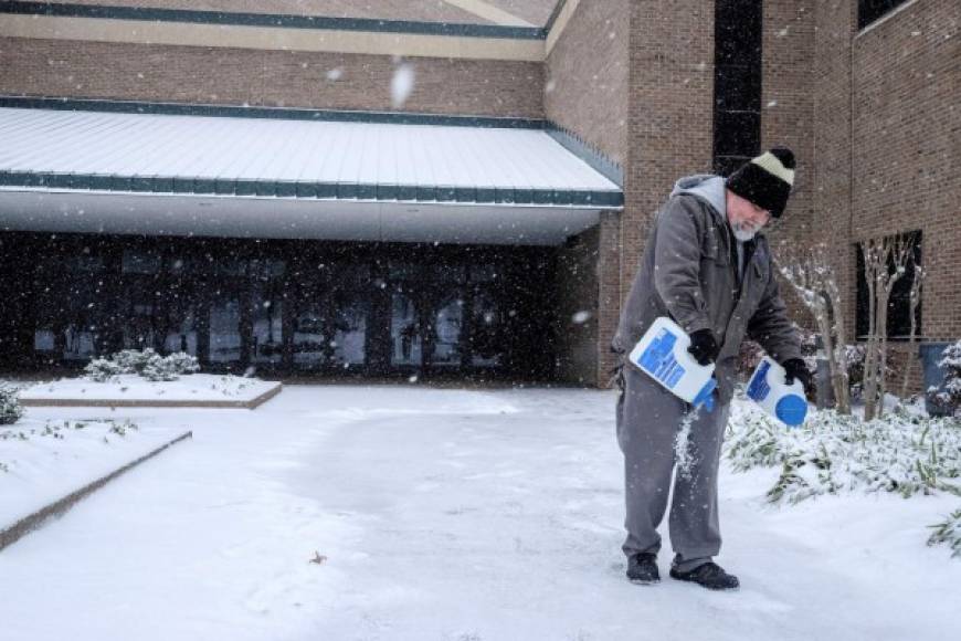 Un pastor echa sal para derretir la nieve de la entrada de su iglesia en un barrio de Nashville.