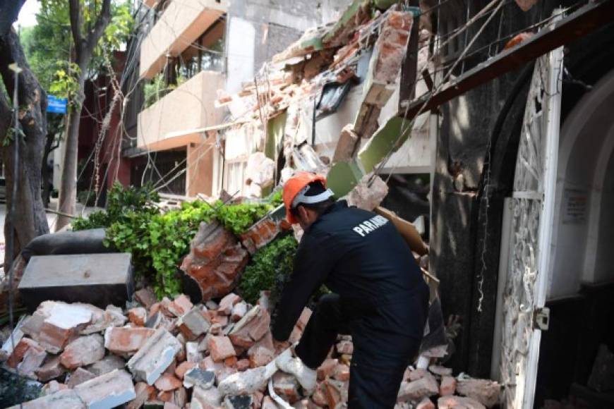 Un agente mexicano busca víctimas entre los escombros.