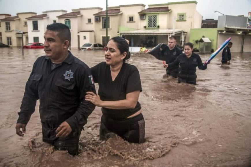 Police officers help a woman cross a flooded street in Culiacan, Sinaloa State, Mexico on September 20, 2018. - Heavy rains have flooded different neighborhoods of Culiacan in the last hours. (Photo by RASHIDE FRIAS / AFP)