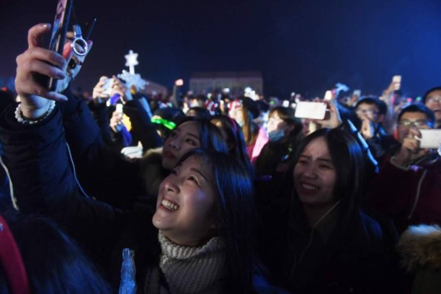 Jóvenes chinas de toman selfis en una plaza de Pekín.