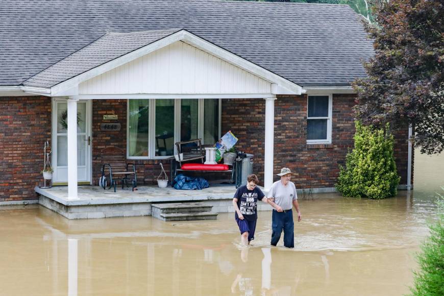 (FILES) In this file photo taken on July 28, 2022 a couple abandons their home flooded by the waters of the North Fork of the Kentucky River in Jackson, Kentucky. - A series of "once-in-a-millennium" rainstorms have lashed the United States in recent weeks, flooding areas baked dry by long-term droughts, as human-caused climate change brings weather whiplash. And scientists warn that global warming means once-rare events are already much more likely, upending the models they have long used to predict possible disasters -- with worse to come. (Photo by LEANDRO LOZADA / AFP)