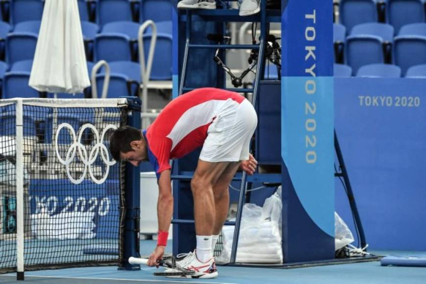 Djokovic recogiendo la raqueta después de reventarla contra la red.