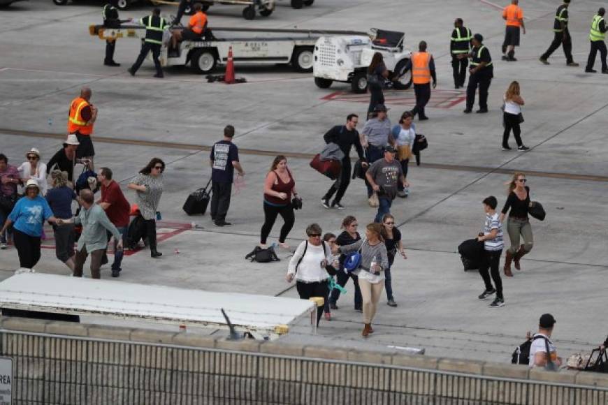 Las personas que se encontraban en la pista del aeropuerto buscan refugio para protegerse del tiroteo.